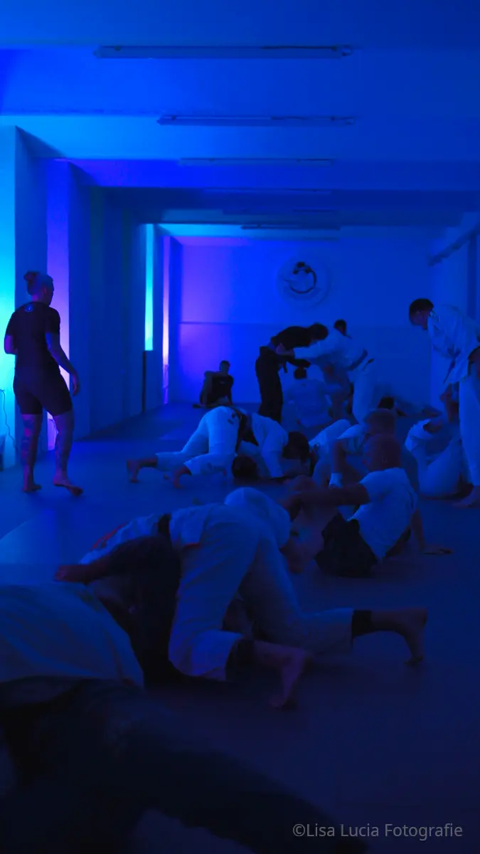Disco Open Mat bei Hocus Chokus BJJ Wien – zahlreiche Paare rollen im Gi beim offenen Training unter blauem Stimmungslicht