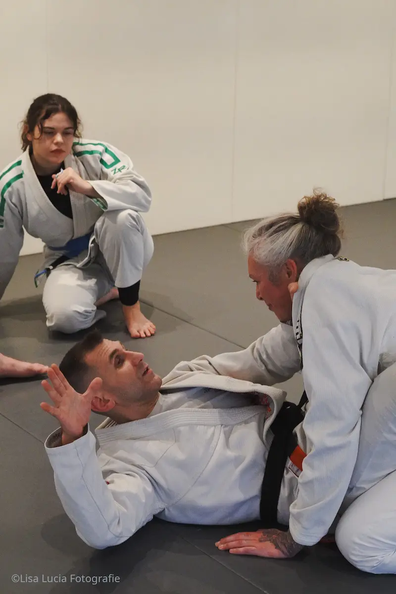 Gi-Training im Brazilian Jiu-Jitsu bei Hocus Chokus Wien – Schwarzgurt arbeitet aus der Closed Guard, Partnerin schaut zu